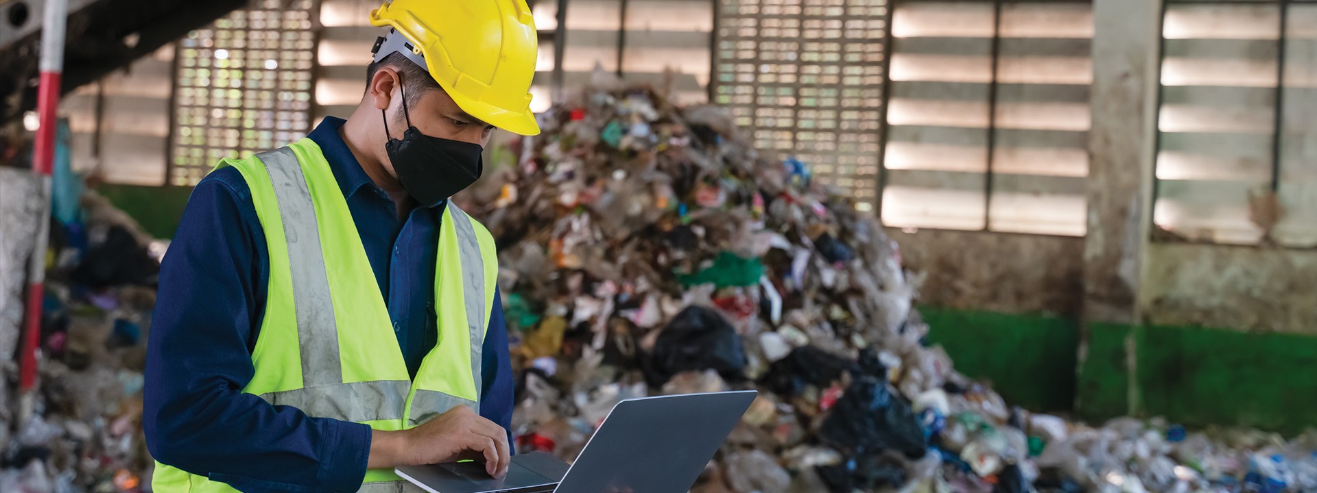 A waste management engineer in protective gear analyzes recycling processes at a landfill site, ensuring efficiency and sustainability.